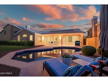 A backyard pool at twilight, surrounded by lounge seating and an illuminated patio, perfect for relaxation and entertaining at 29227 N 44Th St, Cave Creek, AZ 85331