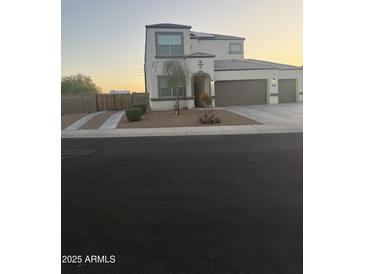 Two-story home featuring a three car garage, stucco siding, a landscaped yard, and concrete driveway at 3012 N 310Th Ln, Buckeye, AZ 85396