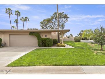 Charming single-story home featuring a lush front lawn and mature landscaping, including palm trees at 7552 N San Manuel Rd, Scottsdale, AZ 85258