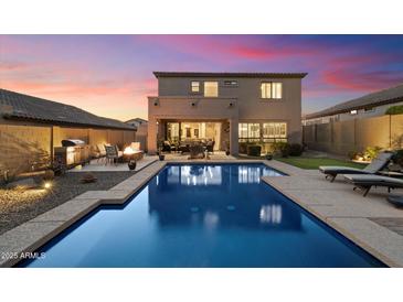 This home features a backyard oasis with a private pool, fire pit, grill, and putting green at 8733 E Jacaranda St, Mesa, AZ 85207