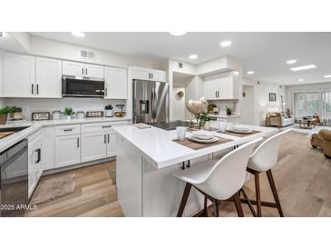 Bright kitchen features white cabinets, stainless steel appliances and an island with seating at 9120 N 86Th Way, Scottsdale, AZ 85258
