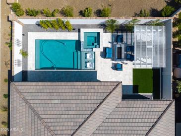 Aerial view of a private backyard featuring a modern pool, spa, and covered patio area with stylish outdoor furniture at 17710 W Guthrie St, Surprise, AZ 85388