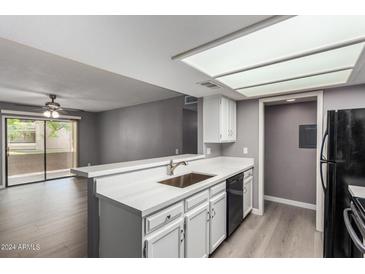 Bright kitchen featuring white cabinets, breakfast bar, updated countertops, and stainless steel sink at 2146 W Isabella Ave # 127, Mesa, AZ 85202