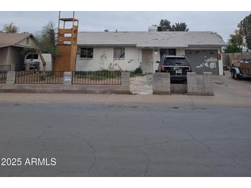 Modest single-story home featuring a fenced yard and attached garage, with a car parked in the driveway at 6536 W Mulberry Dr, Phoenix, AZ 85033