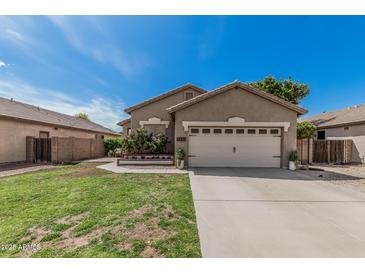 Charming single-story home with a two-car garage, neutral paint, manicured lawn and flower bed at 9463 W Ross Ave, Peoria, AZ 85382