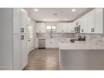 Bright kitchen boasts white cabinets, stainless steel appliances, marble backsplash, and quartz countertops at 119 E Hampton Ave, Mesa, AZ 85210