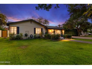 Charming single-story home featuring a well-manicured lawn and inviting landscaping, enhanced by subtle outdoor lighting at dusk at 141 E Bonita Way, Tempe, AZ 85281
