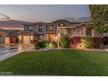 Charming home exterior with lush landscaping, well-manicured lawn and warm inviting lighting at 14294 W Edgemont Ave, Goodyear, AZ 85395