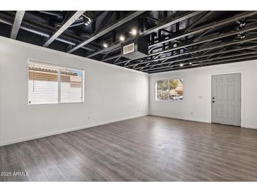 Unfinished basement featuring exposed ceiling, laminate floors, white walls, and natural light from two windows at 1466 E Avenida Fresca --, Casa Grande, AZ 85122
