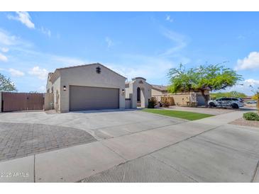 Charming single-story home showcasing a spacious driveway, two-car garage, and inviting desert landscaping at 18437 E Celtic Manor Dr, Queen Creek, AZ 85142