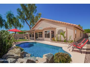 Inviting backyard pool with rock accents, lounge chairs, and covered patio, perfect for outdoor living at 18643 N 73Rd Ave, Glendale, AZ 85308