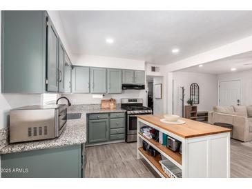 Charming kitchen featuring gray cabinets, granite countertops, and a functional island with a butcher block top at 1919 W Fairmount Ave, Phoenix, AZ 85015