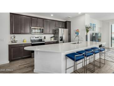 Modern kitchen features stainless appliances, dark cabinets, quartz counters, and stylish seating at the large island at 2511 W Queen Creek Rd # 262, Chandler, AZ 85248