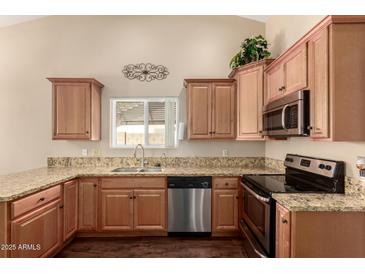 Well-lit kitchen featuring wooden cabinets, granite countertops, and stainless steel appliances at 2753 E Kenwood St, Mesa, AZ 85213
