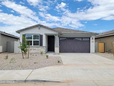 Charming single-story home featuring a two-car garage and desert landscaping under a sunny, partly cloudy sky at 37112 W Prado St, Maricopa, AZ 85138