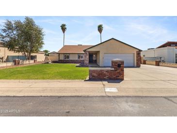 Charming single-story home featuring a lush green lawn, mature trees, and a welcoming two-car garage at 4007 W Thunderbird Rd, Phoenix, AZ 85053