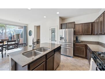 Bright kitchen with an island sink, stainless steel appliances, and an open layout leading to the dining area at 4646 E Maplewood St, Gilbert, AZ 85297