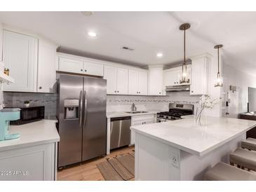 Modern kitchen featuring stainless steel appliances, white cabinets, and quartz countertops with breakfast bar seating at 4950 N Miller Rd # 200, Scottsdale, AZ 85251
