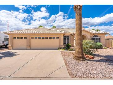 Charming beige home with a three-car garage, tile roof, and well-maintained landscaping at 530 N Jesse Ct, Chandler, AZ 85225