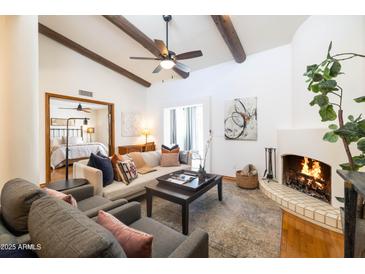 Inviting living room featuring beamed ceilings, a cozy fireplace, and stylish furnishings at 6526 N 13Th Dr, Phoenix, AZ 85013