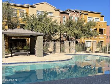 Community pool with inviting turquoise water, lounge chairs, and covered seating area, surrounded by trees and colorful buildings at 900 S 94Th St # 1166, Chandler, AZ 85224