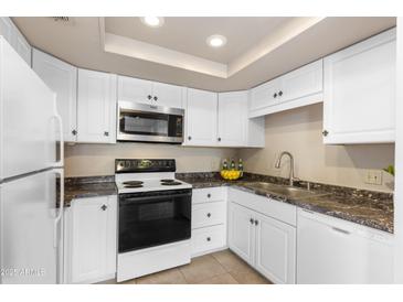 Well-lit kitchen with white cabinets, tile floors, and sleek countertops at 7920 E Camelback Rd # 303, Scottsdale, AZ 85251