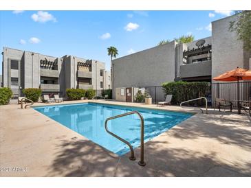 Community pool with lounge chairs and umbrella seating for residents on a sunny day at 8020 E Thomas Rd # 215, Scottsdale, AZ 85251