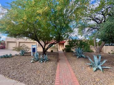 Tan home featuring desert landscaping, a brick walkway, and mature trees offering shade at 9802 N 77Th St, Scottsdale, AZ 85258
