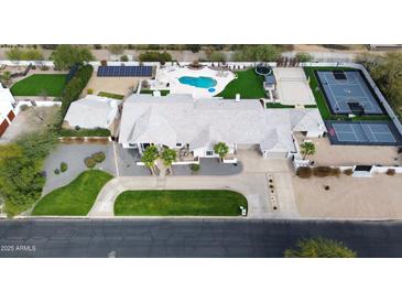 Expansive property featuring a pool, sports court, lush landscaping, and modern solar panels at 6718 E Caron Dr, Paradise Valley, AZ 85253