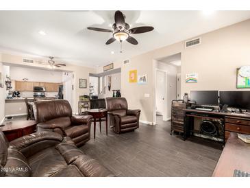 Spacious living room featuring comfortable leather seating and modern entertainment setup, bathed in natural light at 9646 N 94Th Ave, Peoria, AZ 85345