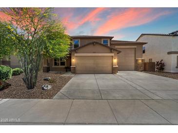 Charming home with a three-car garage, manicured landscaping, and a beautiful sunset backdrop at 12217 W Planada Ln, Sun City, AZ 85373