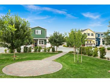 Green lawn and a walkway lead to colorful homes with covered porches in the distance at 16875 N 12Th St # 35, Phoenix, AZ 85022