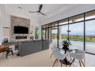 Contemporary living room with a stone fireplace, comfortable seating, and sliding glass doors leading to the outdoors at 15332 E Hidden Springs Trl, Fountain Hills, AZ 85268