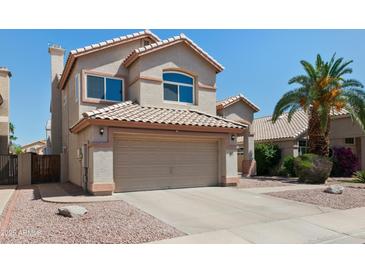 Two-story tan home featuring a two-car garage, complemented by desert landscaping and a palm tree at 162 W El Freda Rd, Tempe, AZ 85284