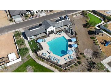 Aerial view of the community pool, featuring ample seating, umbrellas and a green space in a gated community at 17247 W Daley Ln, Surprise, AZ 85387