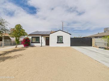 Charming single-story home with a fresh exterior, solar panels, desert landscaping, and a private driveway gate at 2628 W Marshall Ave, Phoenix, AZ 85017