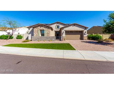 Charming single-story home featuring stone accents, a two-car garage, and a well-manicured lawn at 30857 N 128Th Dr, Peoria, AZ 85383