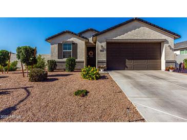 Charming single story home with a brown two car garage and colorful desert landscaping at 36204 W San Sisto Ave, Maricopa, AZ 85138