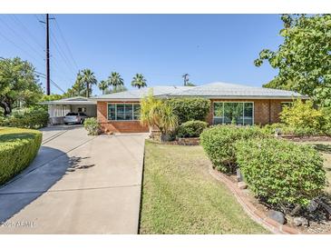 Charming brick home with a well-manicured front yard and covered parking at 1945 E Solano Dr, Phoenix, AZ 85016