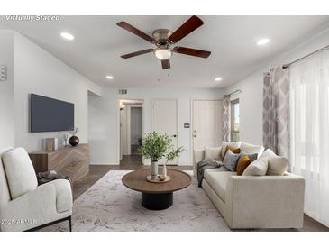 Bright living room featuring a ceiling fan, modern furniture and stylish decor and front door at 5221 E Tunder Cir, Phoenix, AZ 85044