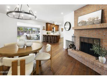 Open concept dining area featuring brick fireplace, wood table and chairs, and modern lighting at 613 E Vista Ave, Phoenix, AZ 85020