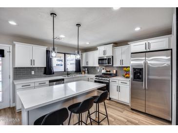 Bright kitchen with stainless steel appliances, white cabinets, stone countertops and pendant lighting at 18642 N 13Th Ave, Phoenix, AZ 85027