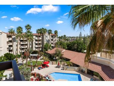 Community pool with lounge chairs, palm trees, and a building with red tile roof at 4200 N Miller Rd # 503, Scottsdale, AZ 85251