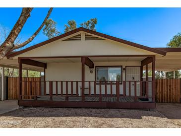 Charming house featuring a welcoming porch and adjacent carport providing convenient covered parking at 115 S Stardust Ln, Apache Junction, AZ 85120
