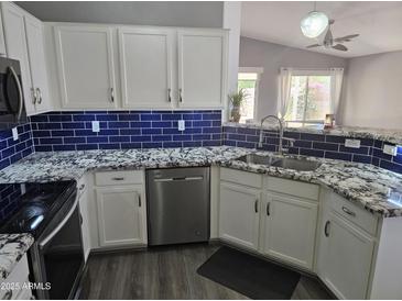 Modern kitchen featuring stainless steel appliances, granite countertops, and a blue tile backsplash at 11760 N 153Rd Ave, Surprise, AZ 85379
