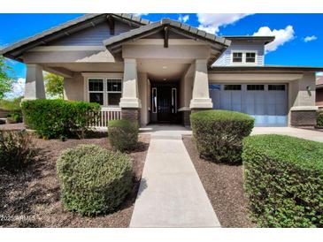 Charming home featuring a well-manicured lawn, covered porch, and an attached two car garage at 14770 W Voltaire St, Surprise, AZ 85379