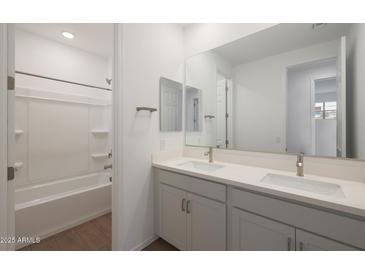 Bright bathroom features double sinks, a large mirror, and a shower-tub combination at 17319 W Via Dona Rd, Surprise, AZ 85387