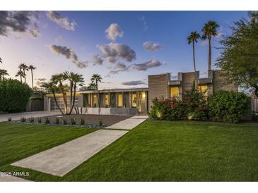 Charming exterior view of home with manicured lawn, mature landscaping, and a long driveway leading to a two-car garage at 20 W Canterbury Ln, Phoenix, AZ 85023