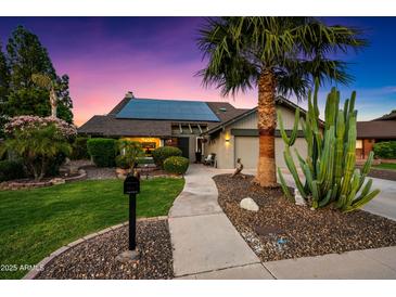 Charming home with well-manicured lawn, lush landscaping, desert plants, and modern solar panels, bathed in the warm glow of twilight at 2066 E Lockwood St, Mesa, AZ 85213