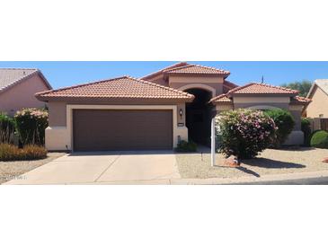 Charming single-story home featuring a terracotta roof, brown garage door, and desert landscaping at 3928 N 151St Ave, Goodyear, AZ 85395
